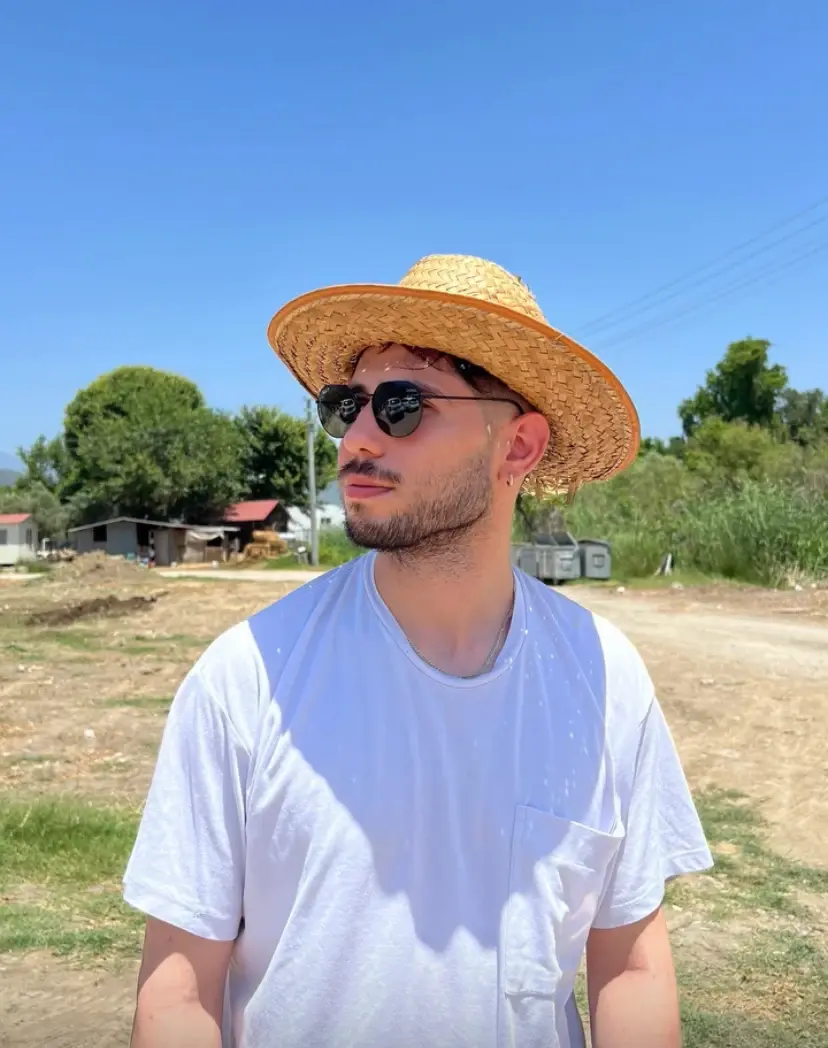Ahmet Yasir Demir wearing a straw hat and sunglasses outdoors.